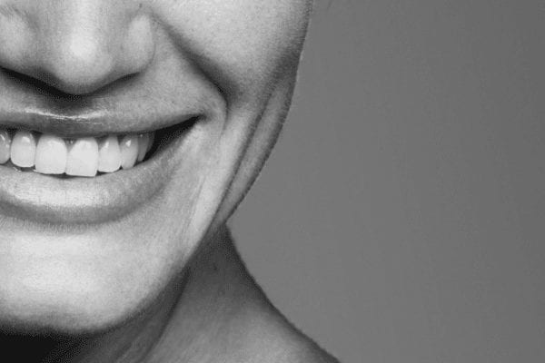 Smilende person med hvide tænder i sort-hvid close-up