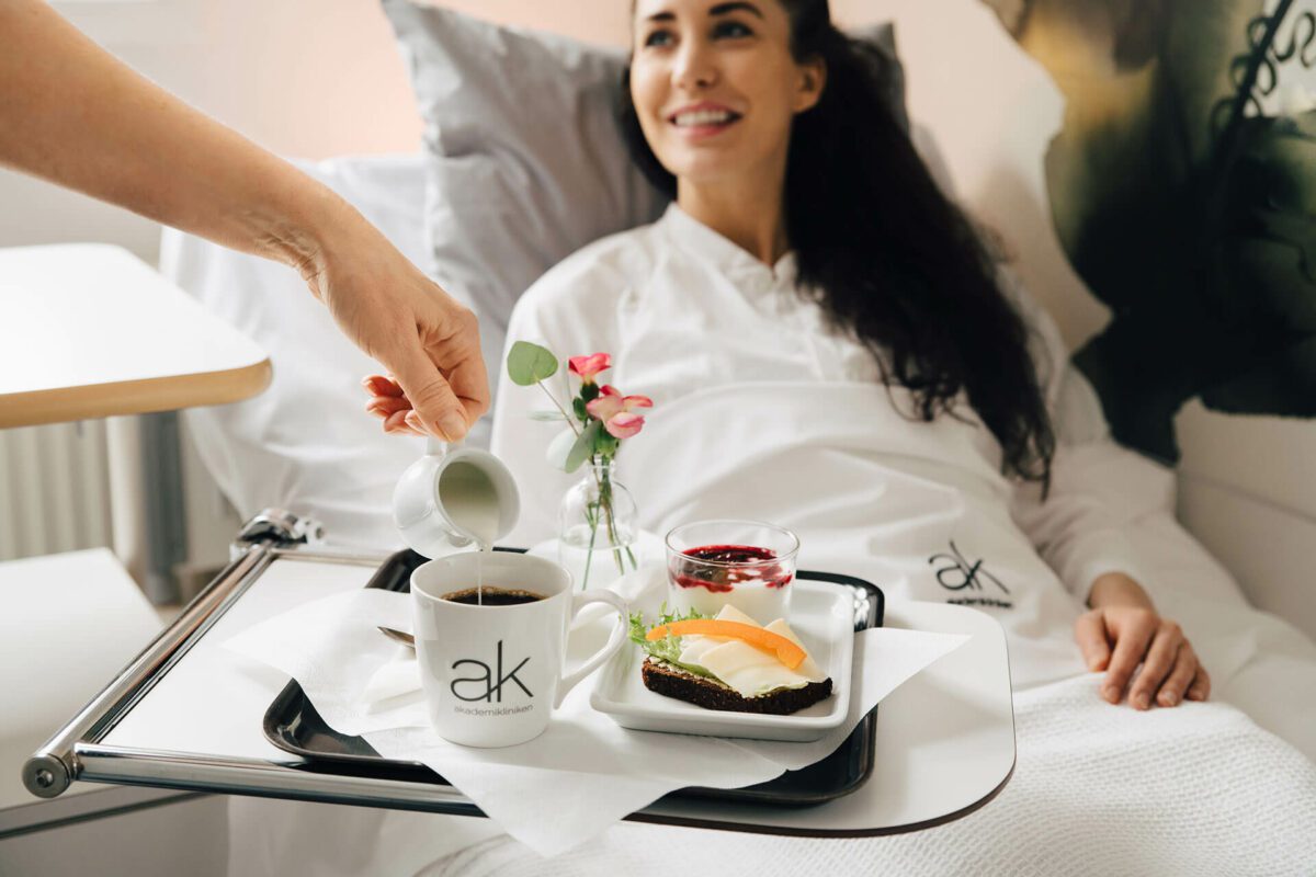 Morgenmad serveres på sengen med kaffe, frugt og blomster