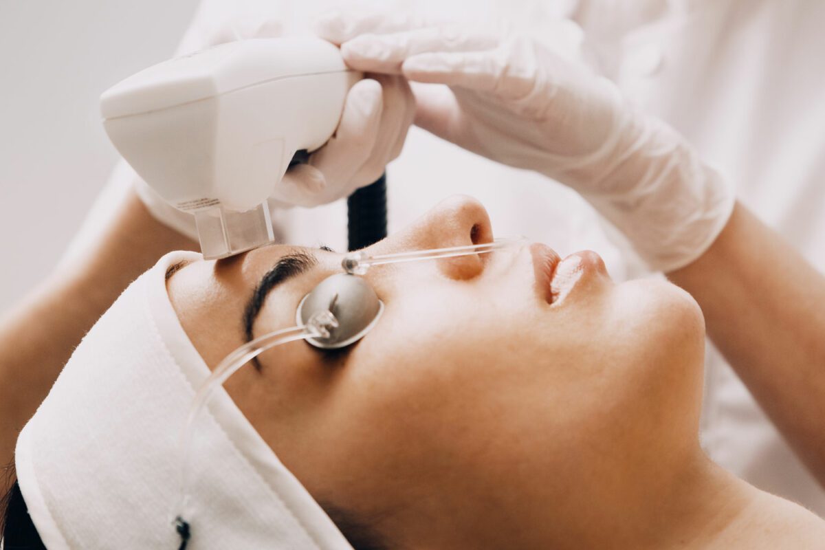 Kvinde modtager laserbehandling i ansigtet hos kosmetisk klinik