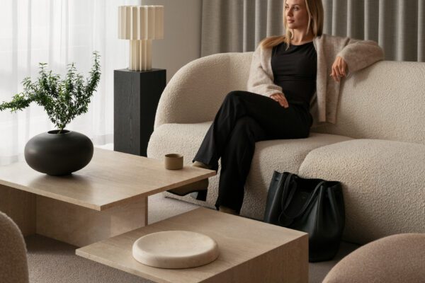 Kvinde i sort kjole sidder i beige teddy-sofa med moderne bord og lampe