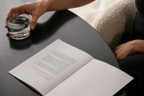 Person med glas vand ved skrivebord med åben brochure
