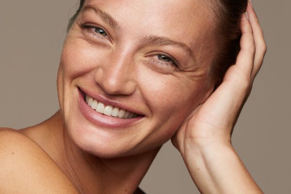 Smilende kvinde med hånden ved håret og naturlig makeup