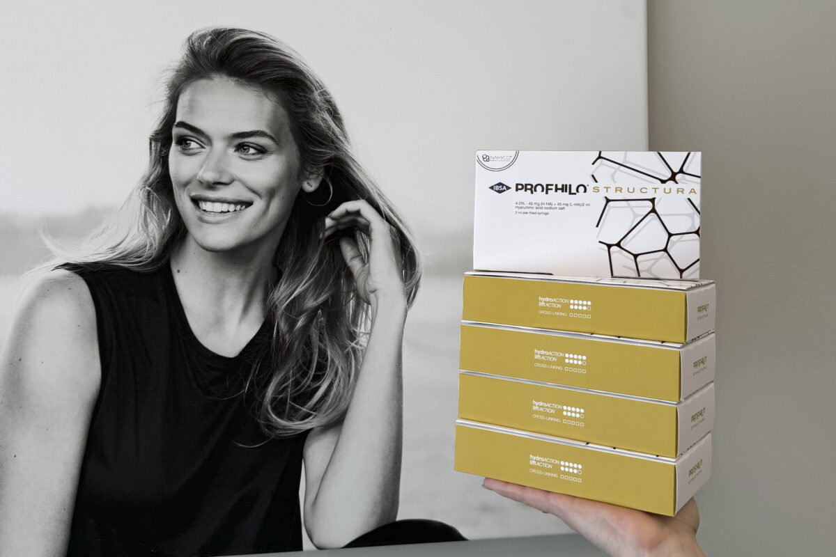 Kvinde smiler ved siden af stablede Profhilo Structura og hydroACTIVE BI-ACTIV produktæsker